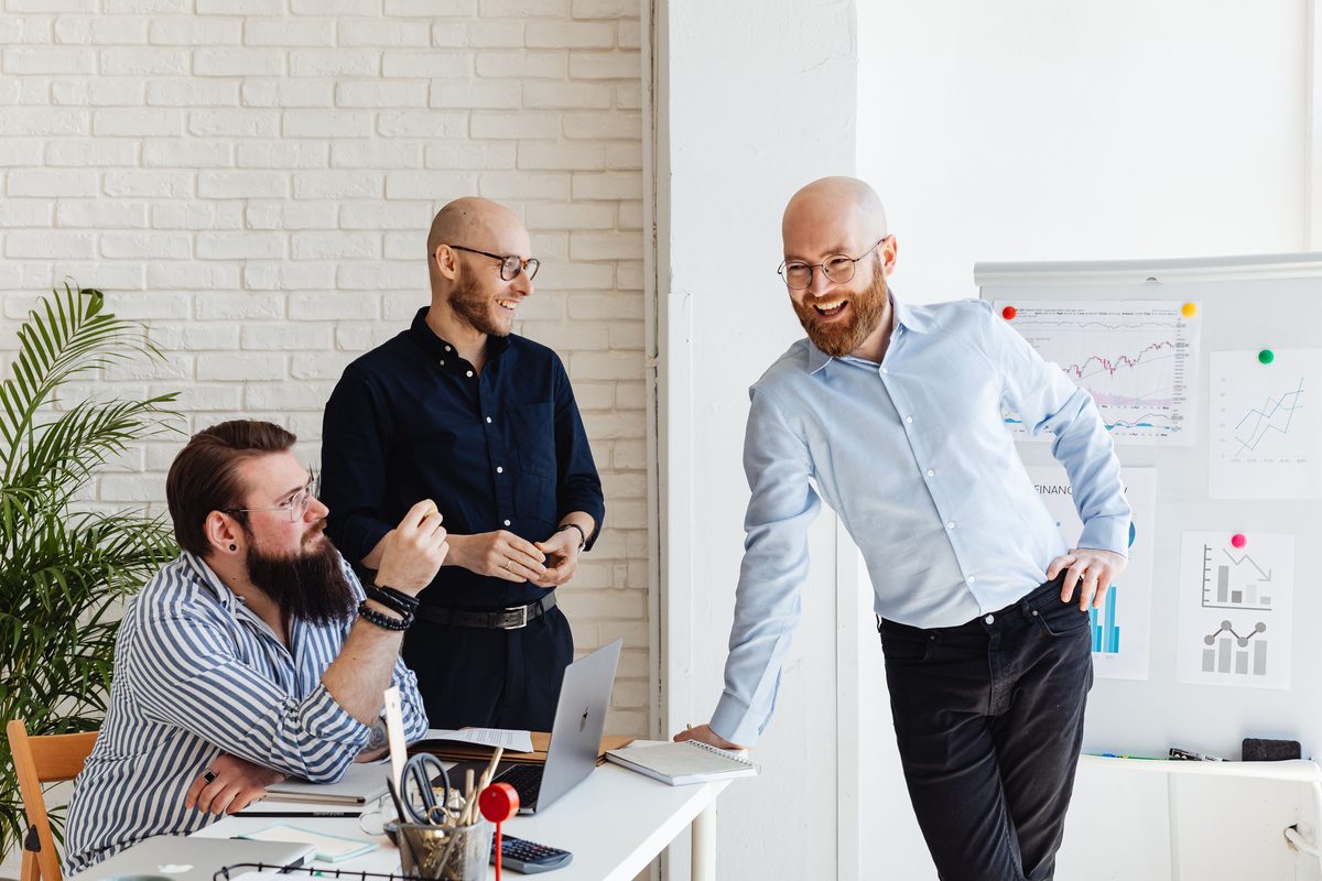 Drie collega's bespreken een strategie bij een whiteboard met cijfers