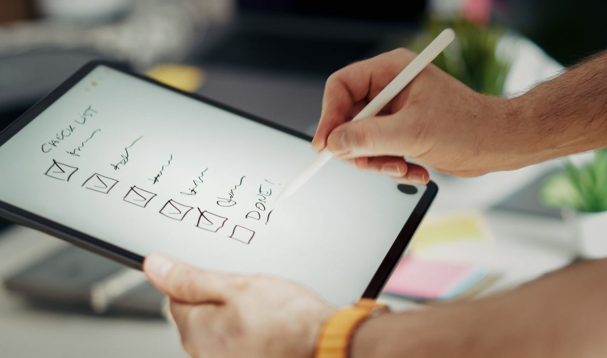Close-up van een hand die een digitale checklist invult op een tablet