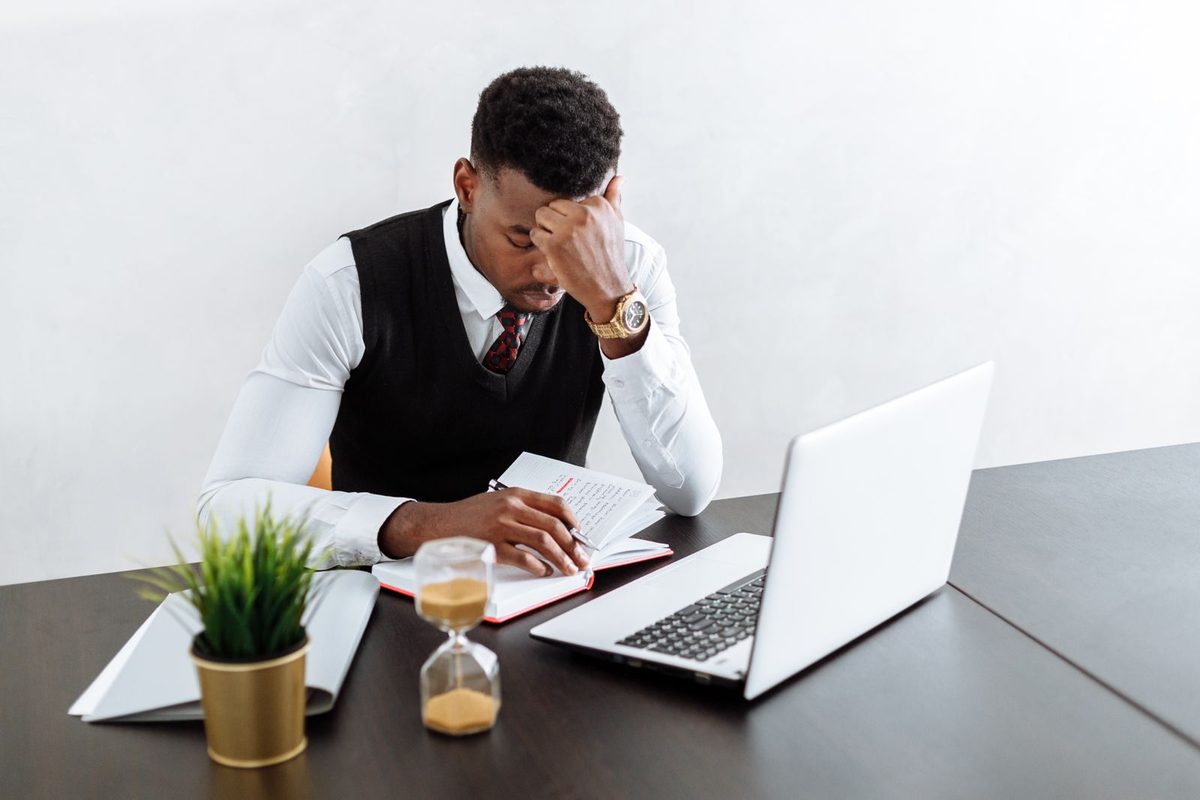 Een man werkt geconcentreerd op zijn laptop, met een zandloper ernaast